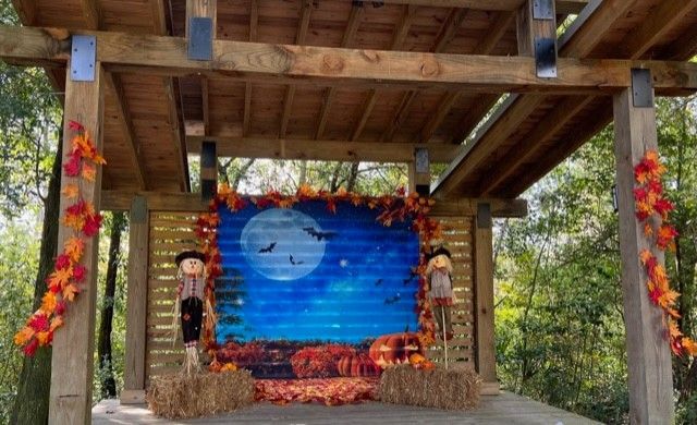 A wooden stage with a painting of a full moon and scarecrows on it.