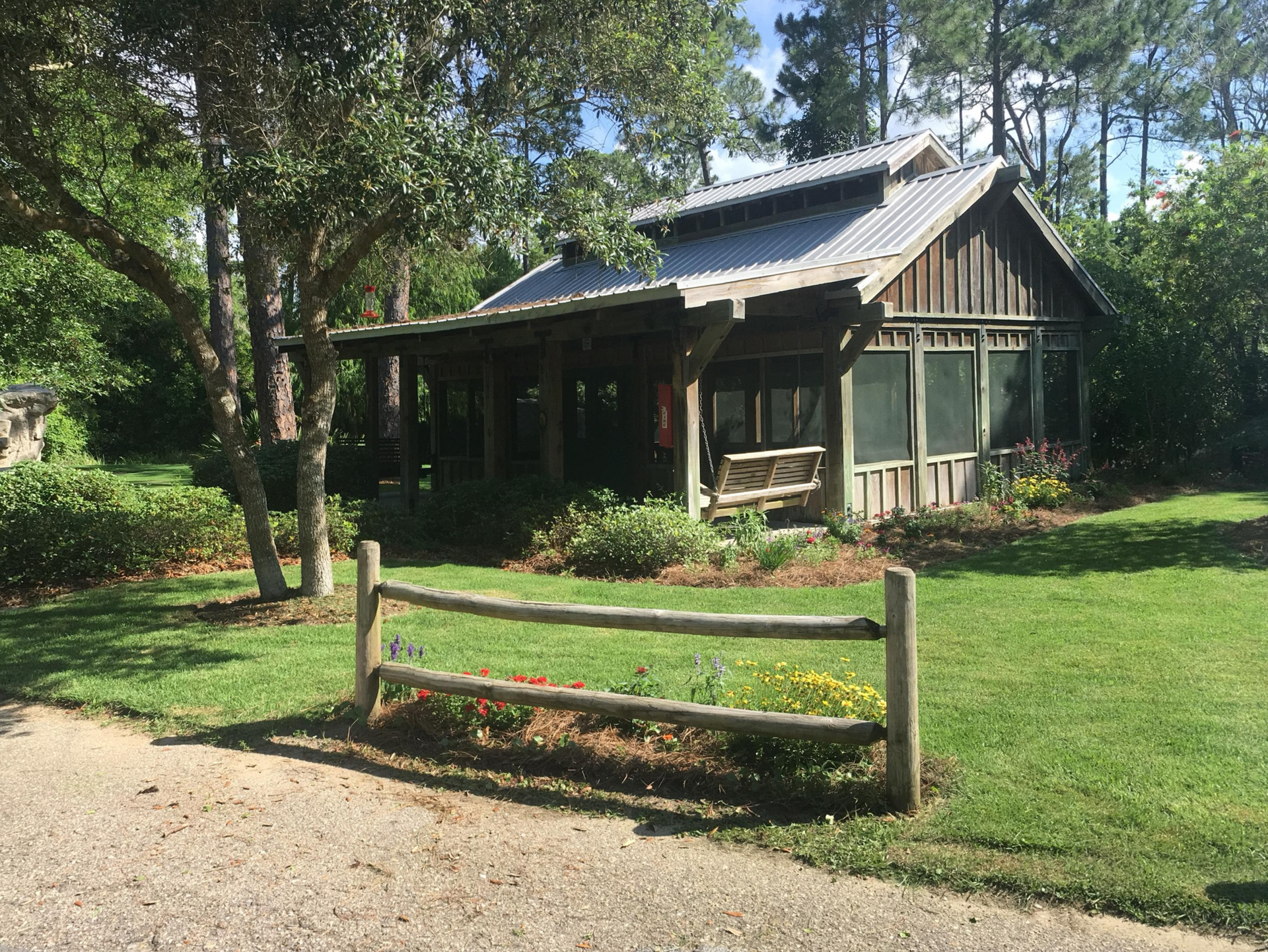 A small house with a screened in porch and a wooden fence in front of it.