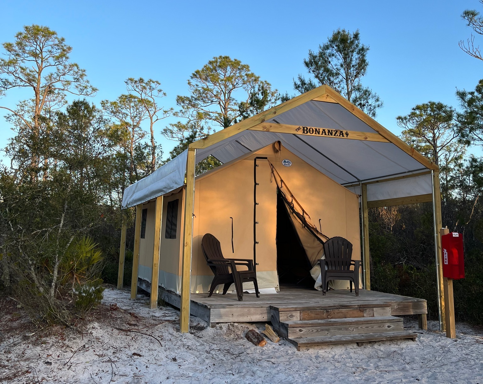A tent with two chairs and a fire extinguisher in front of it at a Primitive Campsite