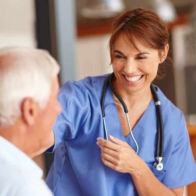 A nurse is smiling while talking to an elderly man.