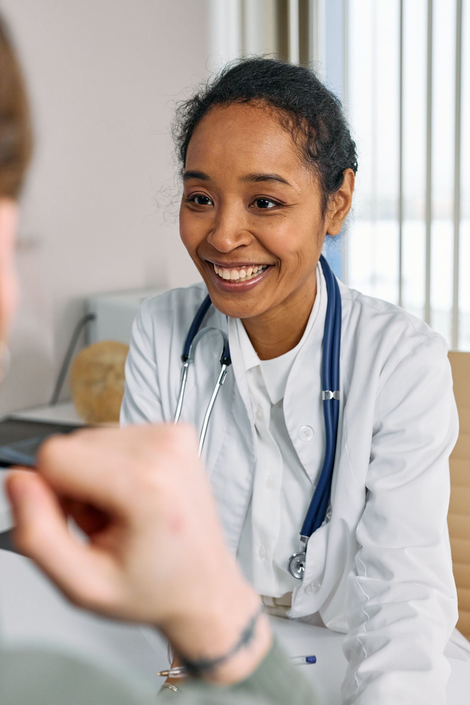 A female doctor is smiling while talking to a patient.