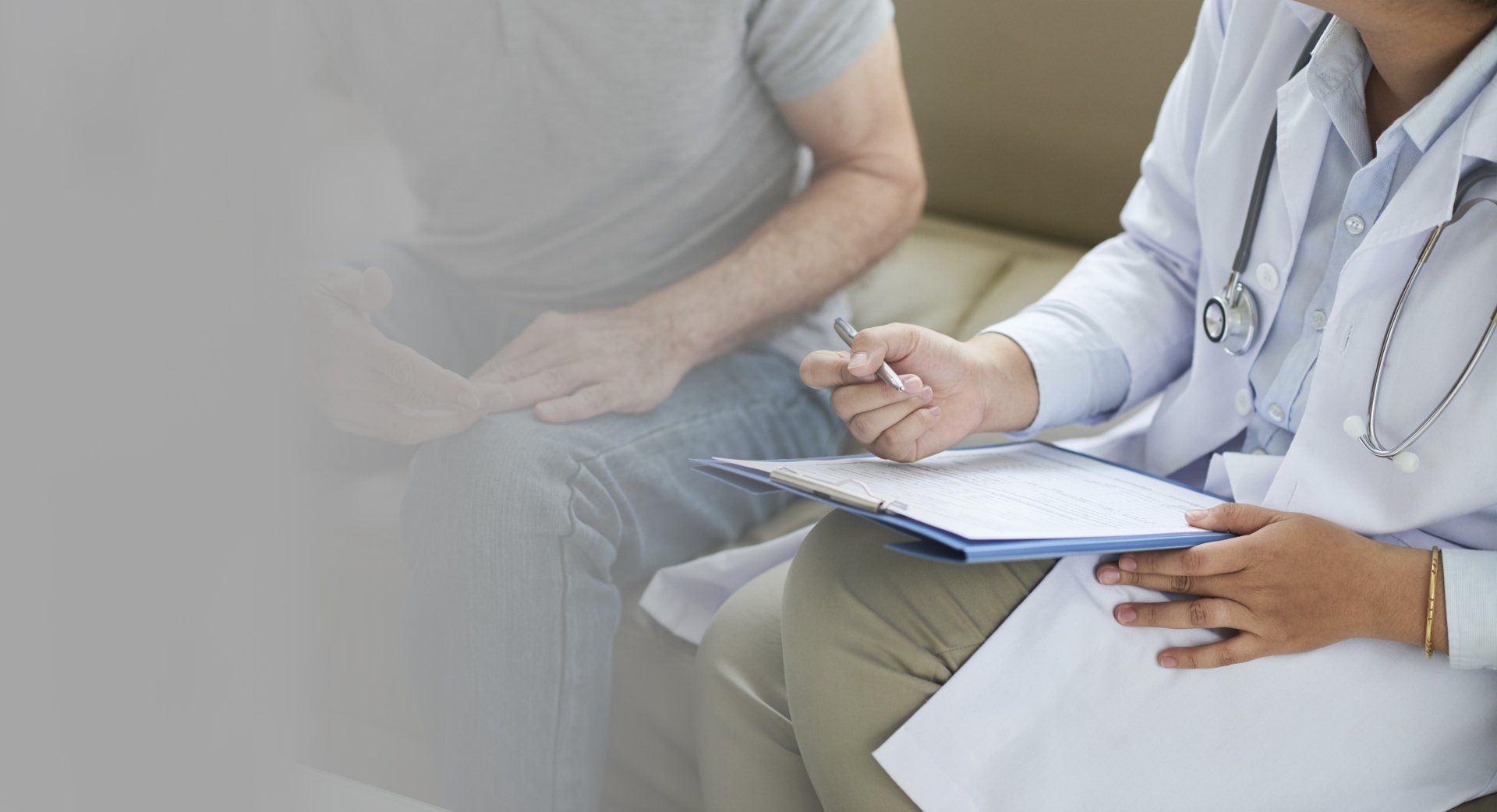 A doctor is talking to a patient who is sitting on a couch.
