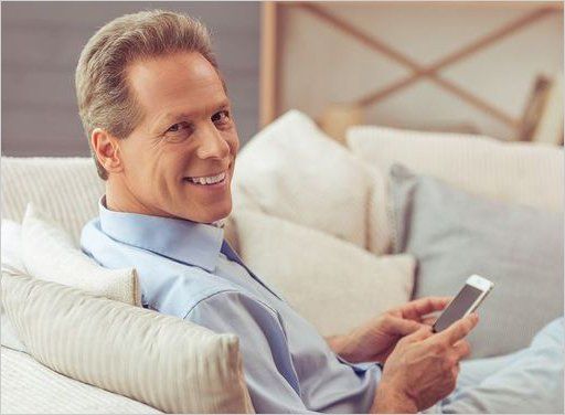 A man is sitting on a couch using a cell phone.