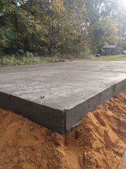 Hands using a trowel to smooth wet concrete in a form, with others nearby.