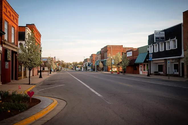 Quiet small-town main street with brick storefronts at dusk and empty roads