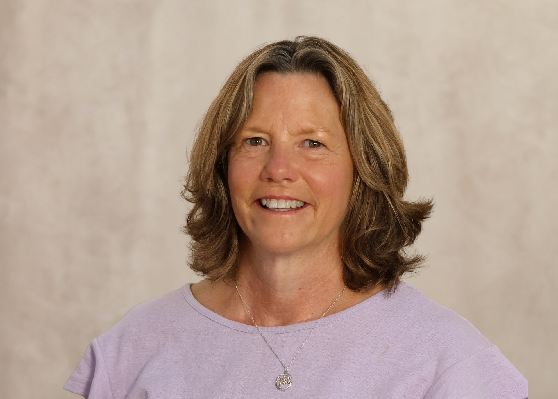 Smiling woman in a light purple top against a neutral background