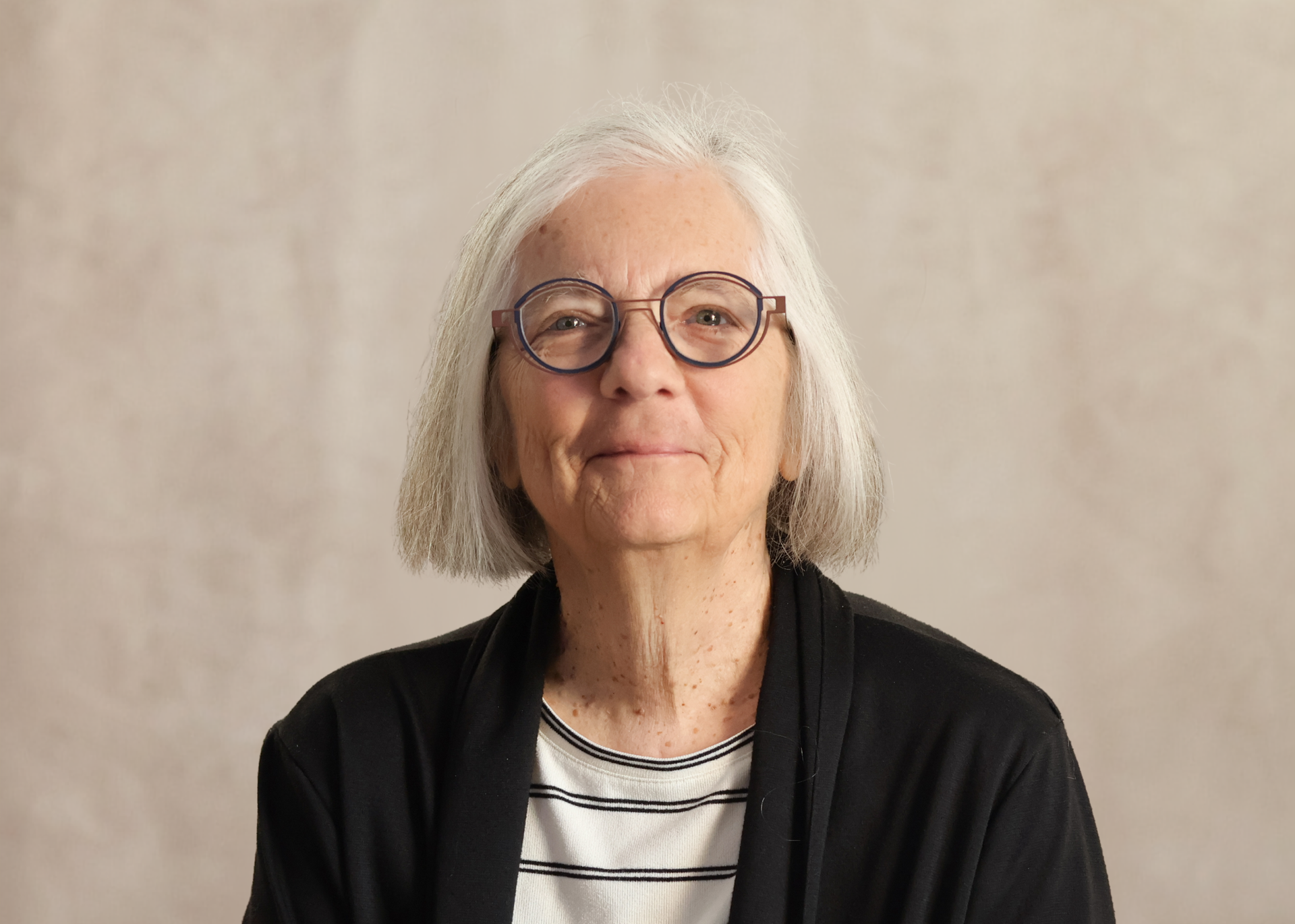 Smiling women in glasses and black and white striped shirt against a neutral background