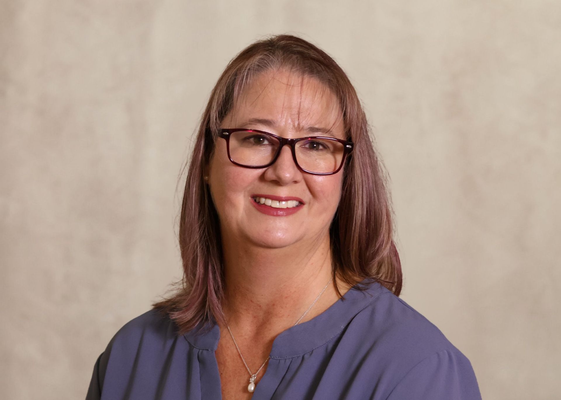 Smiling women in glasses and black and white striped shirt against a neutral background