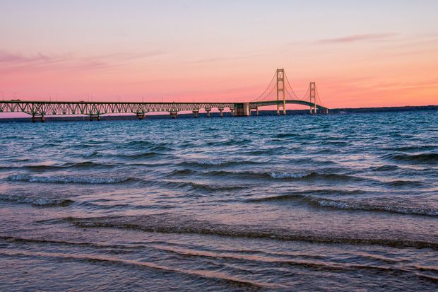 Sunset over a large suspension bridge above rippling ocean waves