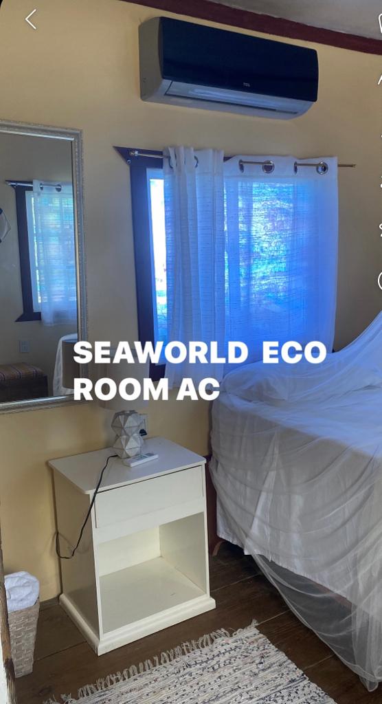 A bedroom with a bed , nightstand , mirror and air conditioner.