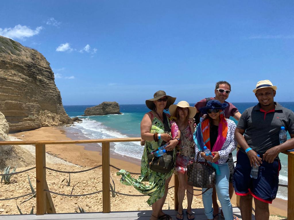 A group of people are posing for a picture on a beach.