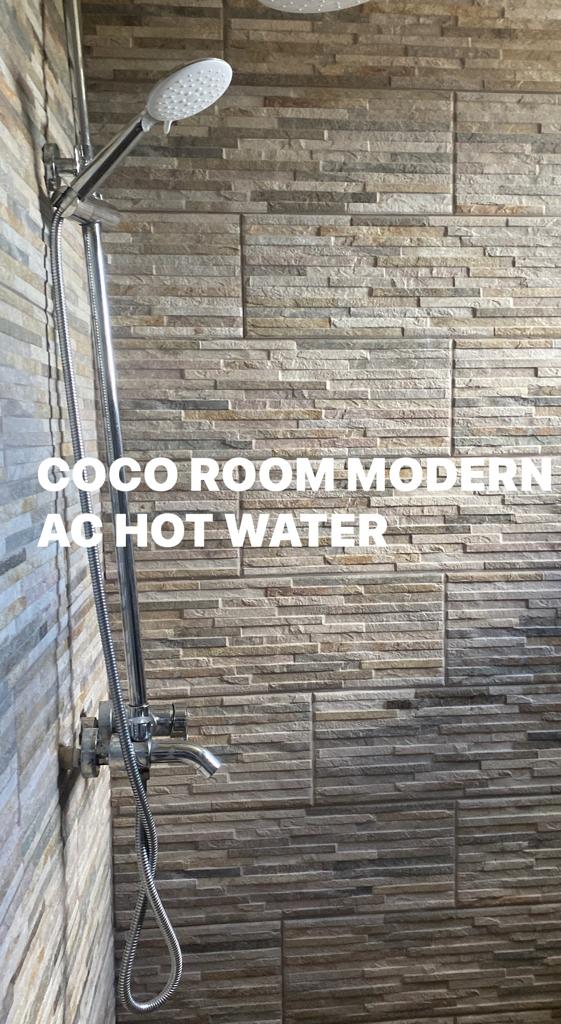 A shower head is hanging from a brick wall in a bathroom.