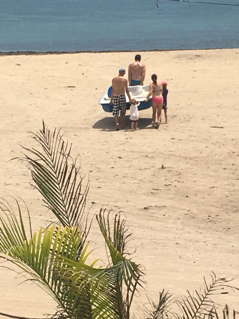 A group of people standing on a beach with a boat in the background