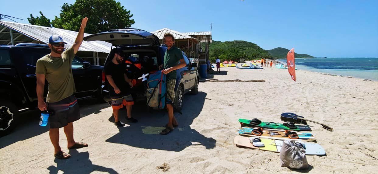A group of people standing on a beach next to a car