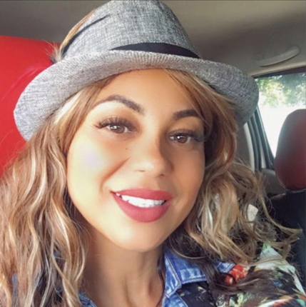 A woman wearing a hat is smiling in a car