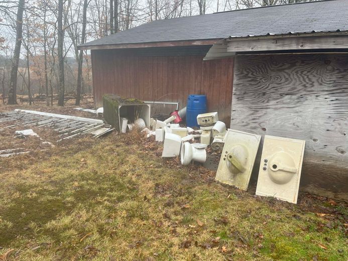A pile of trash is sitting in front of a wooden building.
