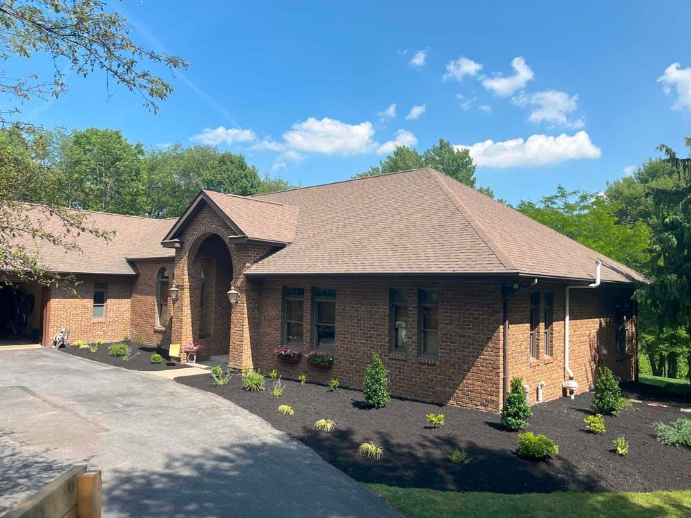 A large brick house with a brown roof and a driveway leading to it.