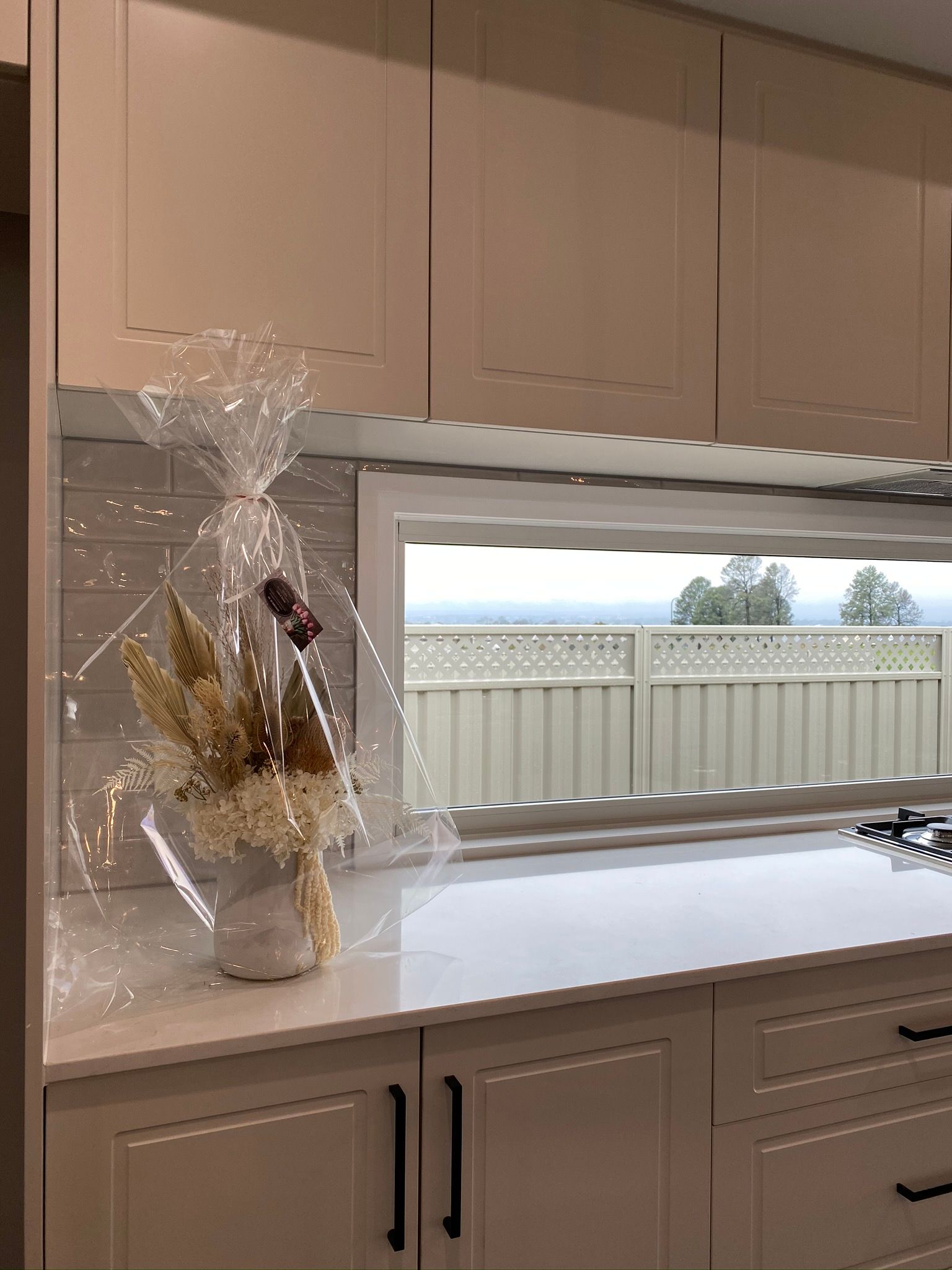 Beautiful Flower on a Countertop With Large Window — Kitchen Renovations in Dubbo, QLD