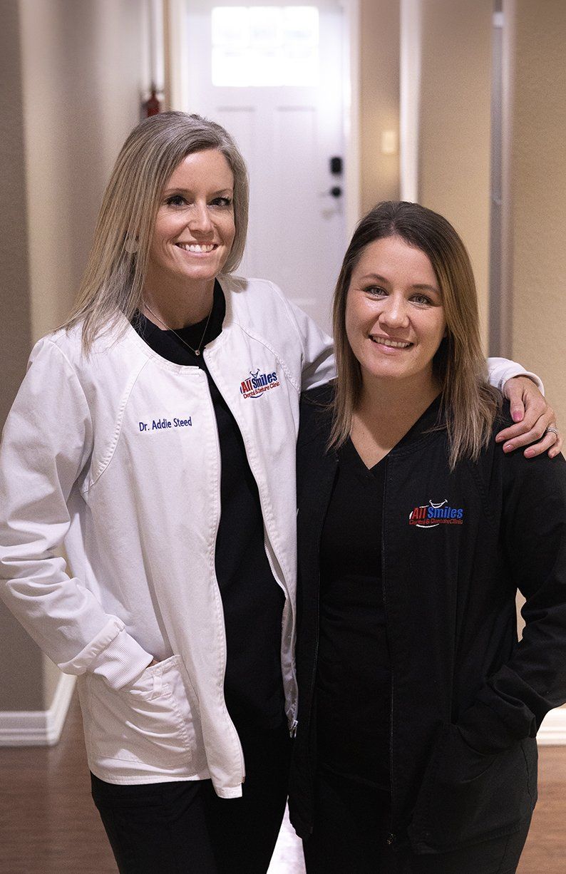Two female doctors are posing for a picture together in a hallway.
