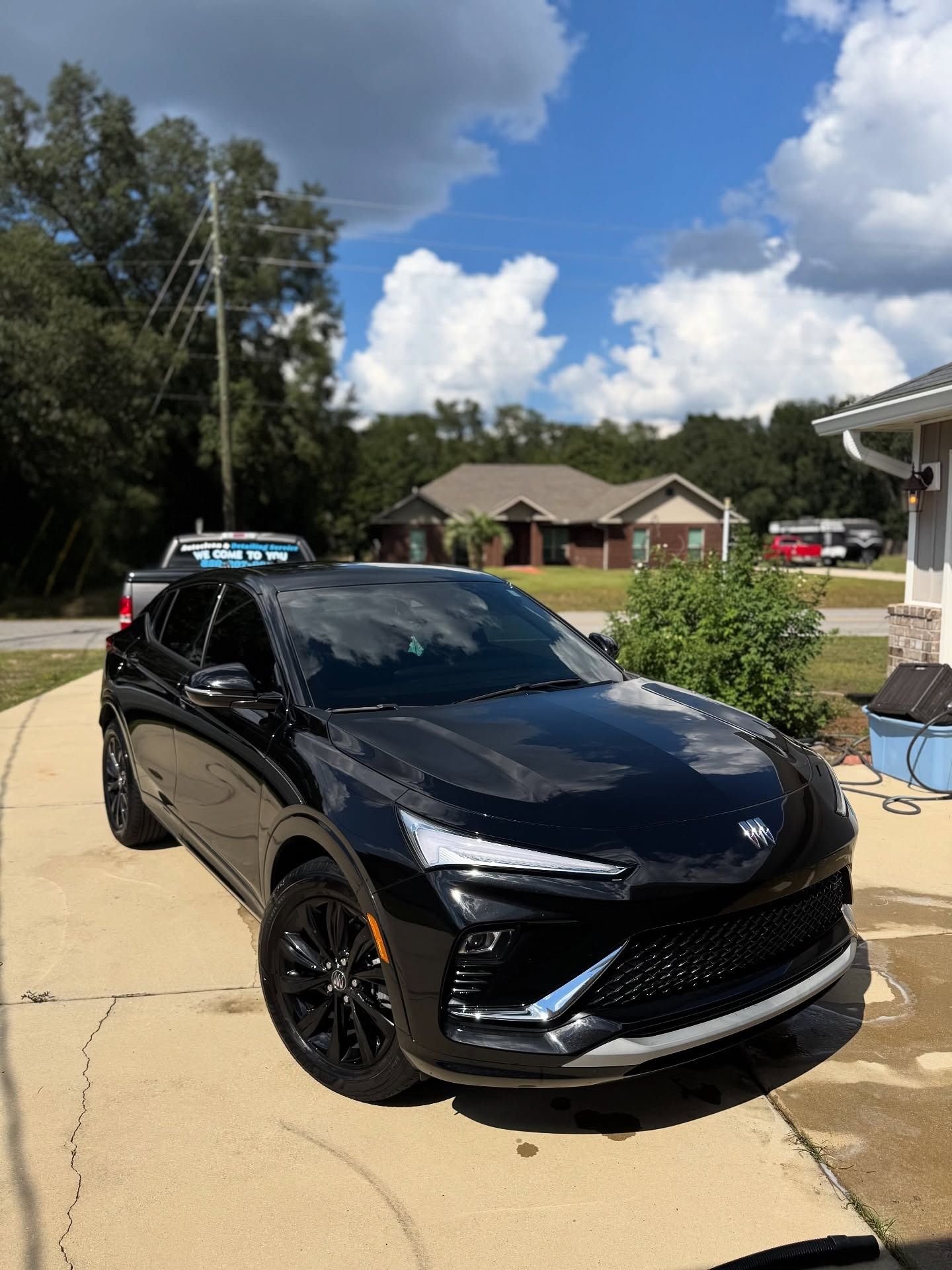 Black SUV parked in a suburban driveway under a partly cloudy sky