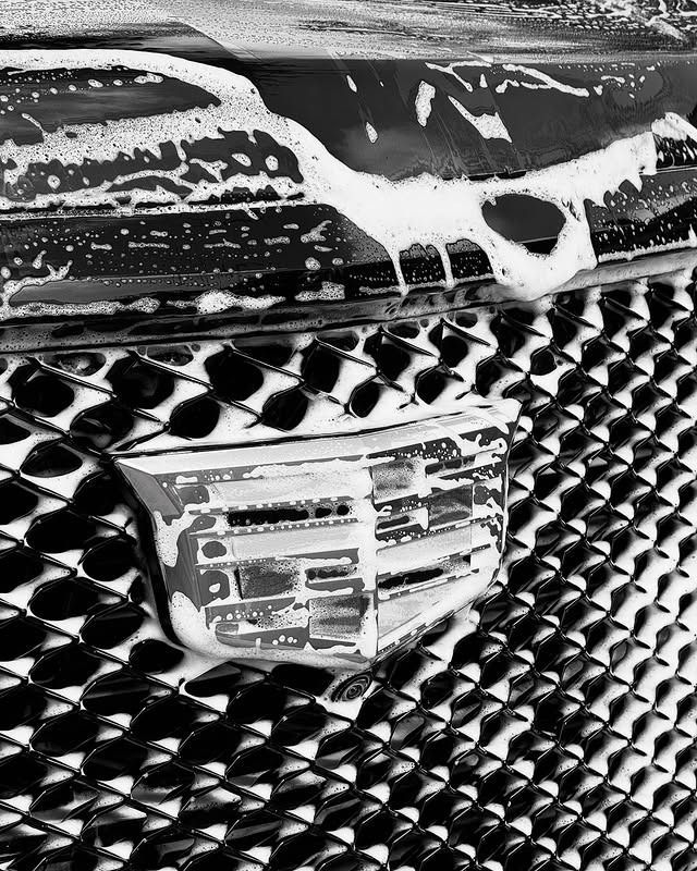 Close-up of a Cadillac grille and crest emblem with white paint streaks above it.