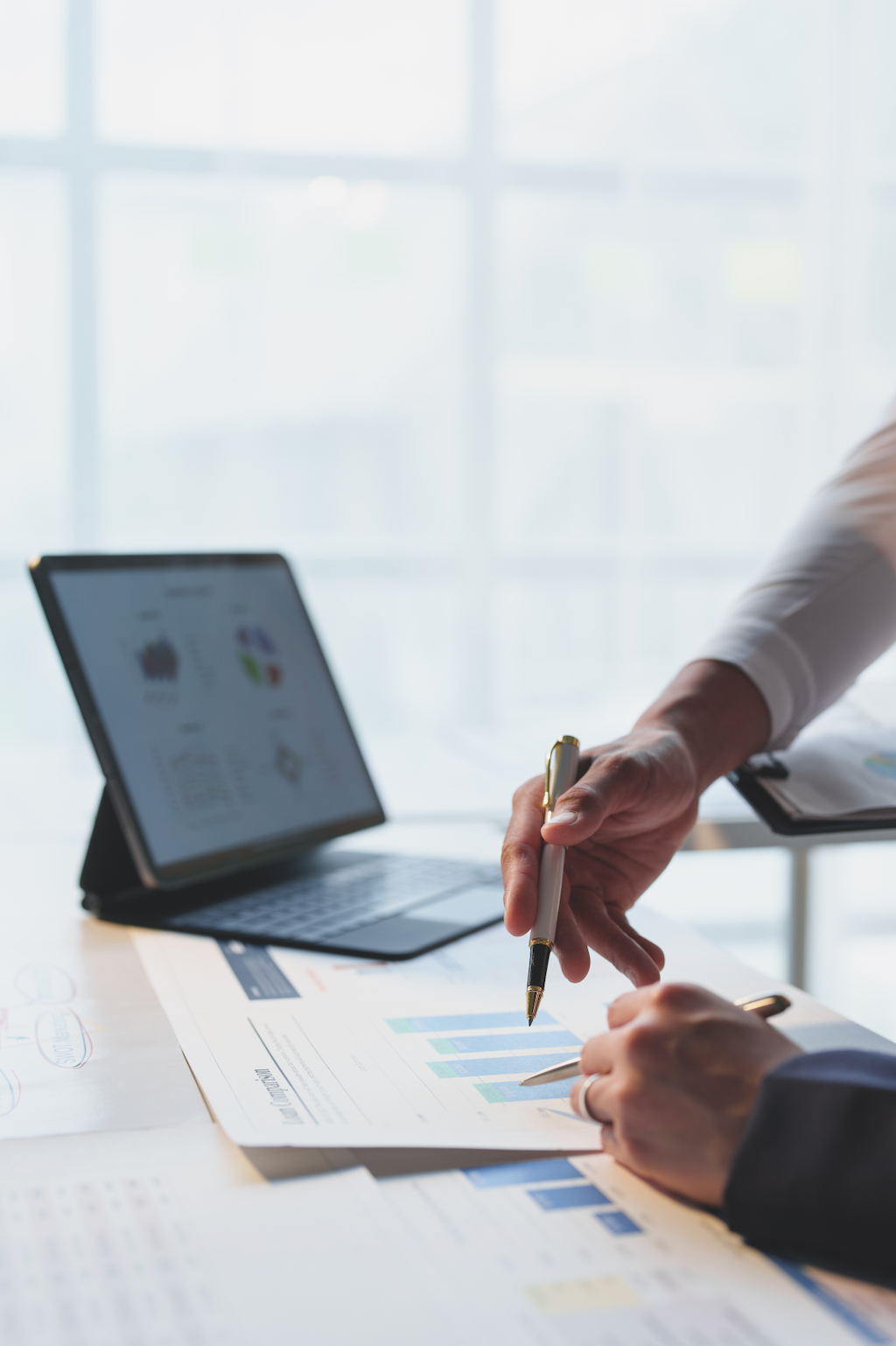 A person is sitting at a table with a laptop and a pen.