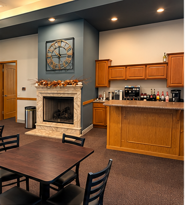Lobby lounge with fireplace, wood tables, and a kitchenette bar area