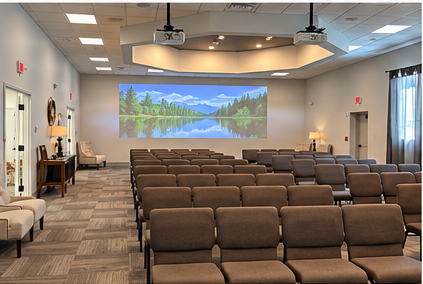 Empty meeting room with rows of brown chairs facing a projected lake landscape