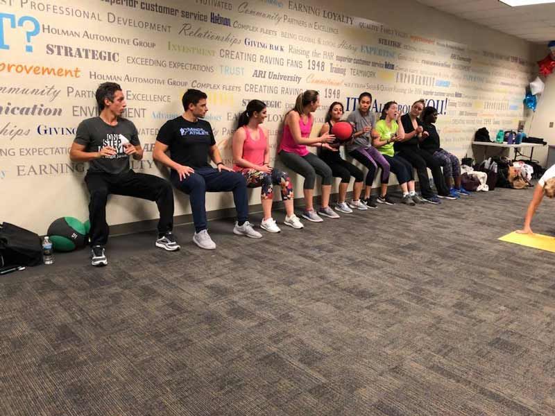 A group of people are doing squats in a gym
