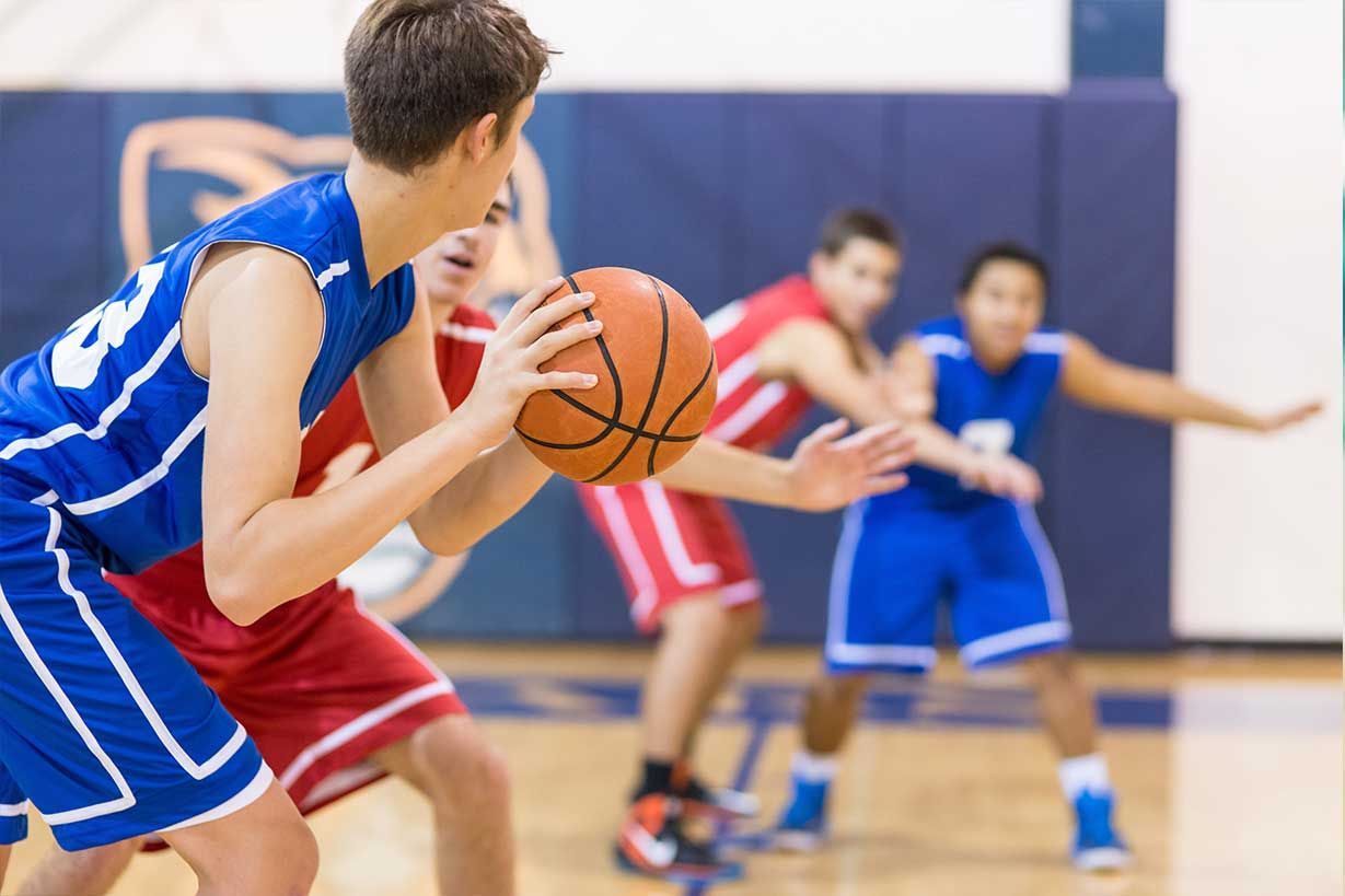 Un grupo de jóvenes juega baloncesto en una cancha.