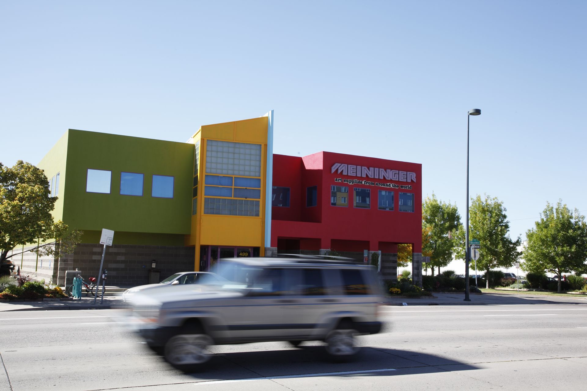 Colorful modern building with a blurred car passing in front on a sunny street