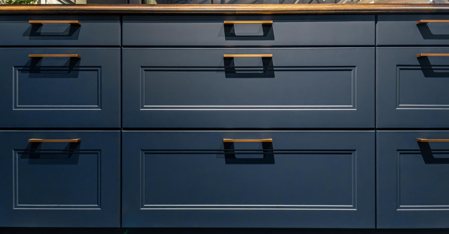 Dark blue dresser drawers with black handles in a close-up view