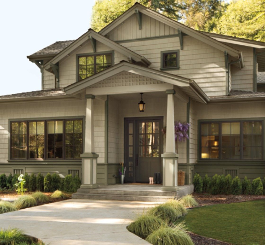 Beige Craftsman-style home with dark brown trim, front porch, and landscaped yard.