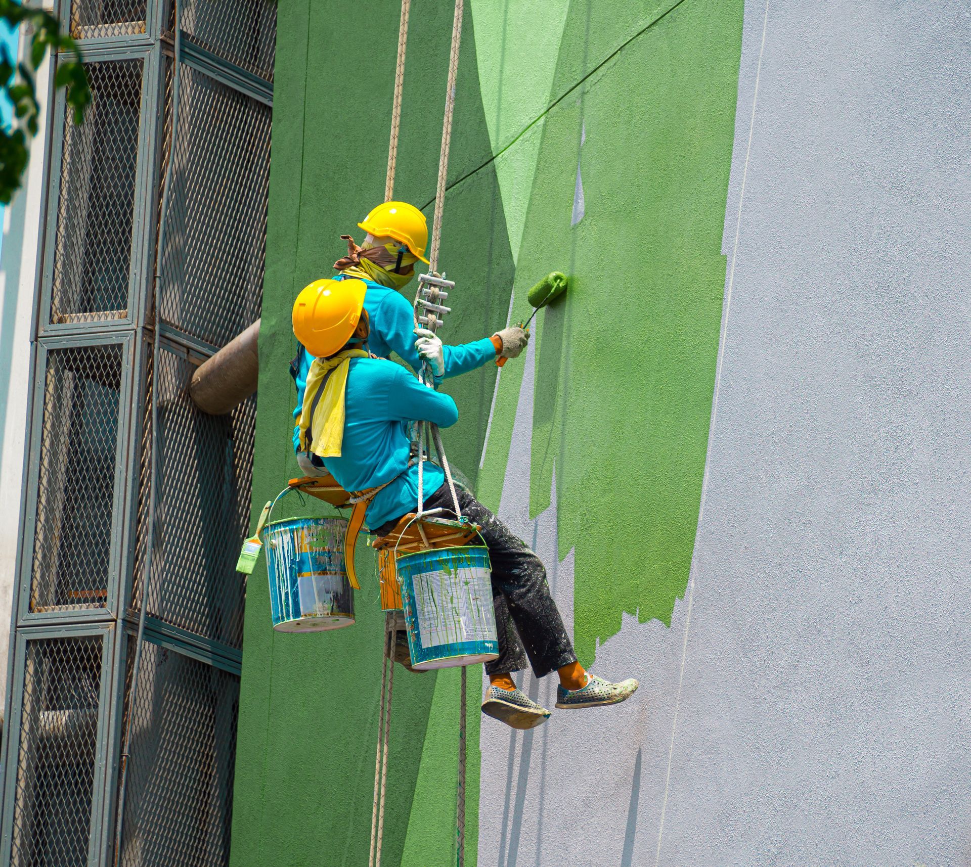 a couple of people are painting a wall on a building .