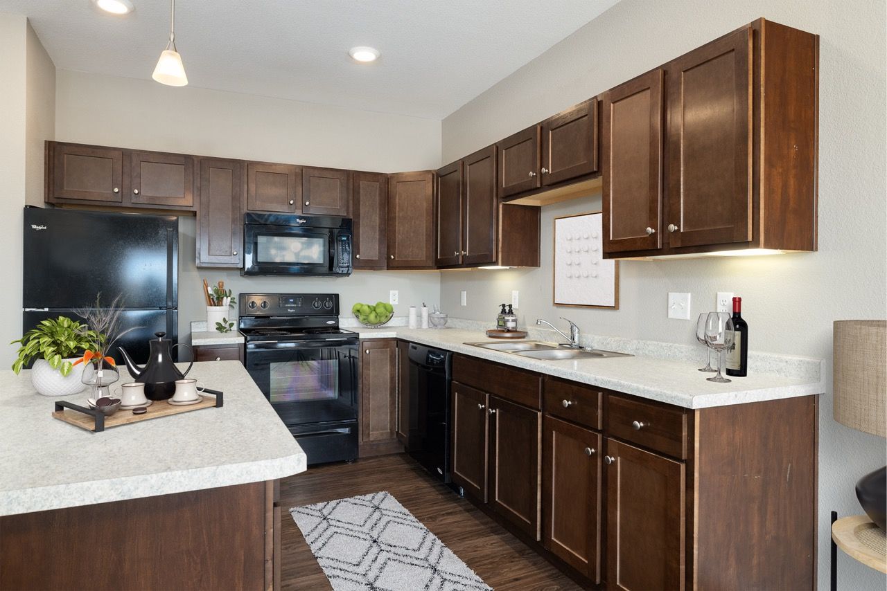 Modern apartment kitchen with dark wood cabinets, light countertop, and stainless appliances.