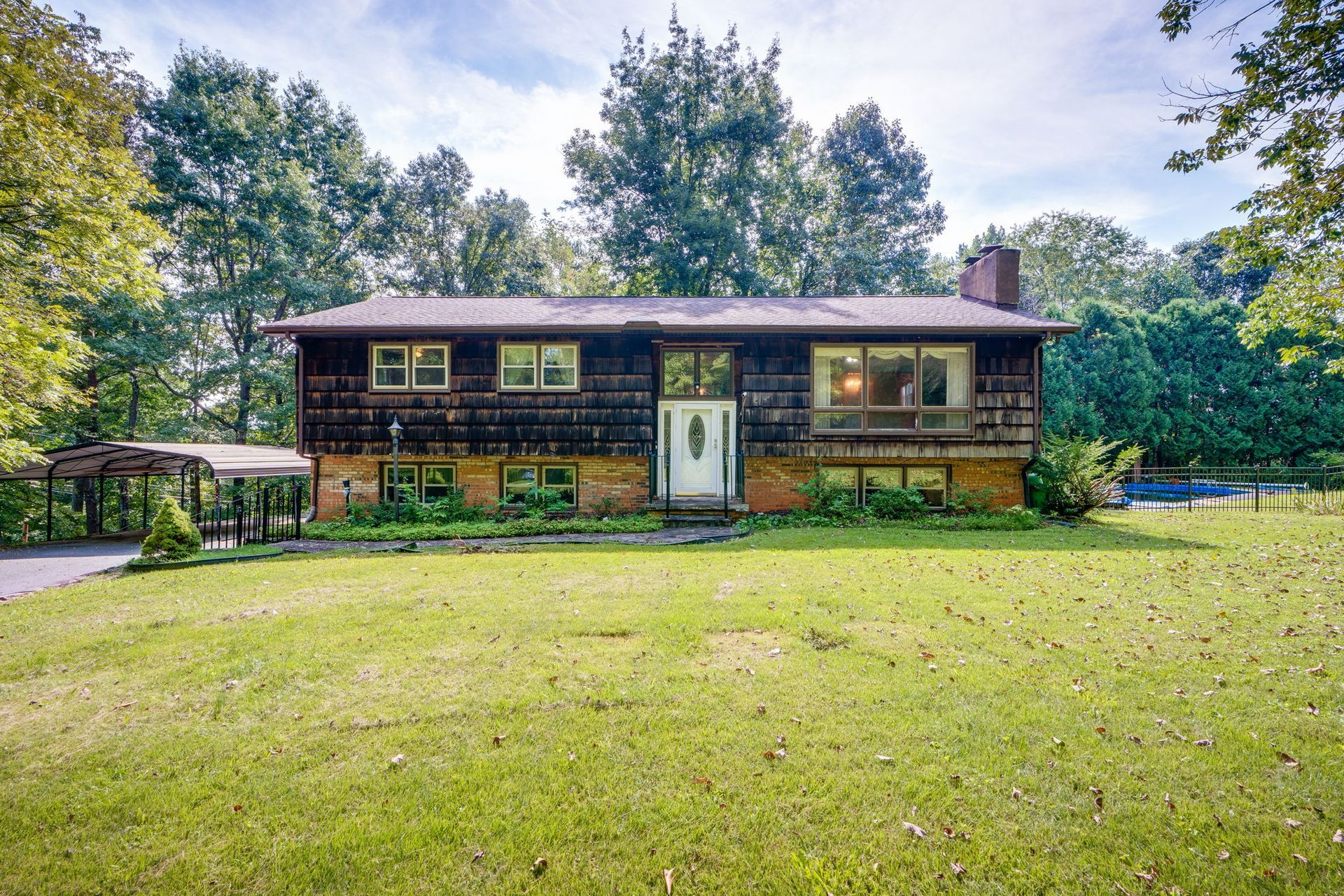Single-story wooden house with a front lawn and trees surrounding it