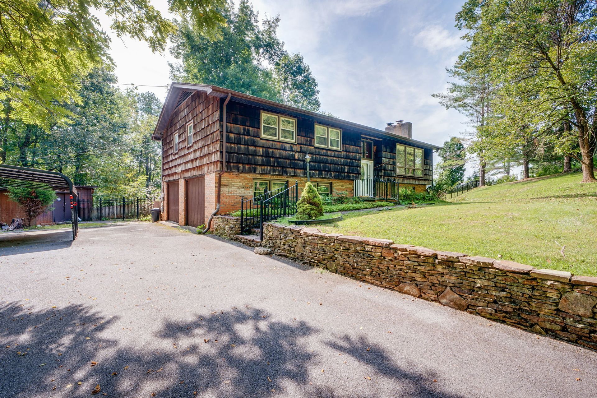 Modern two-story wooden building with glass windows beside a paved driveway and grassy slope