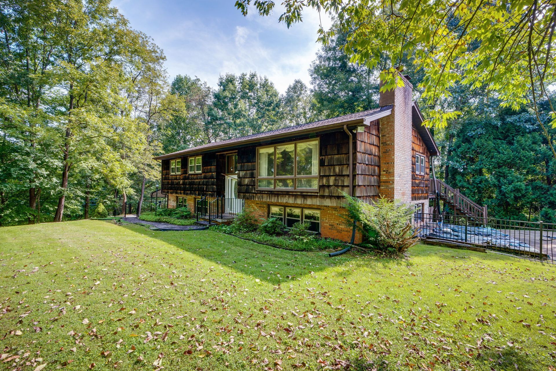 Modern house with wood siding on a grassy lawn surrounded by trees