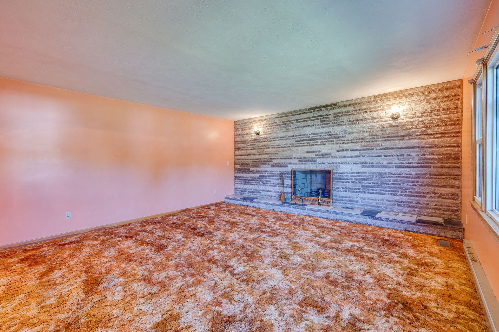Empty living room with carpet, stone accent wall, and fireplace