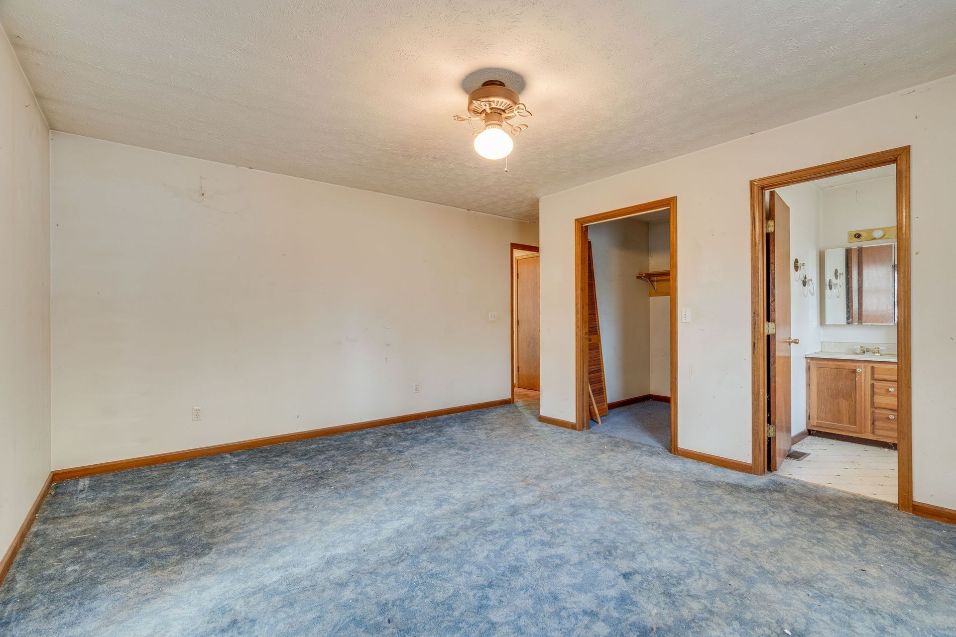 Empty room with blue carpet, white walls, and three doorways.