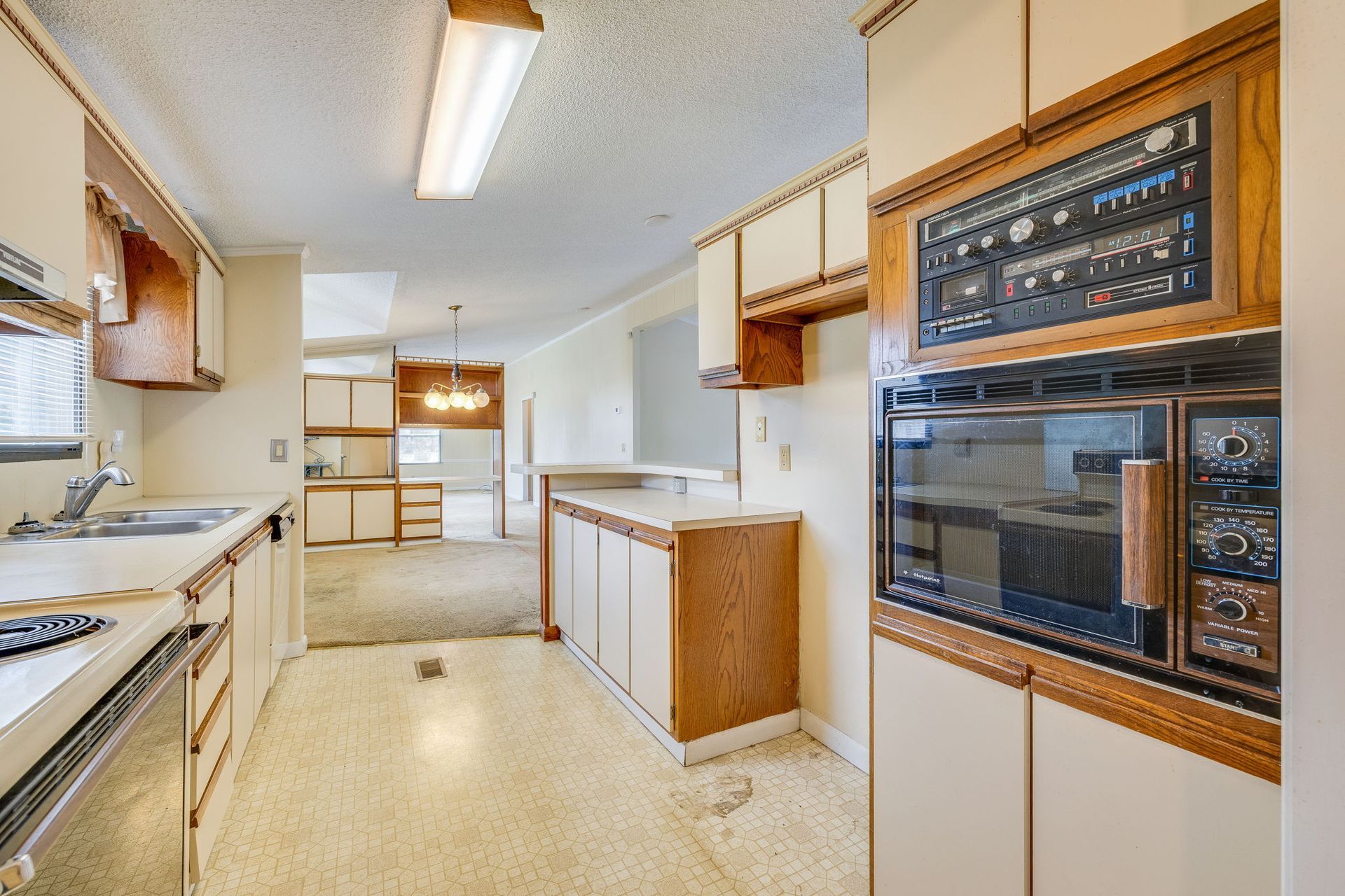 Bright retro kitchen with white cabinets, wood accents, and built-in oven and microwave.