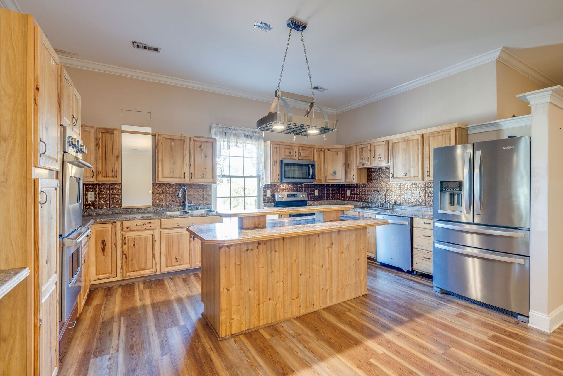 Bright modern kitchen with wooden cabinets, island, stainless steel appliances, and hardwood floors