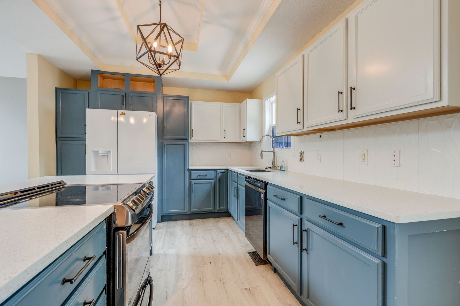 Bright modern kitchen with blue and white cabinets, stainless appliances, and a geometric pendant light.