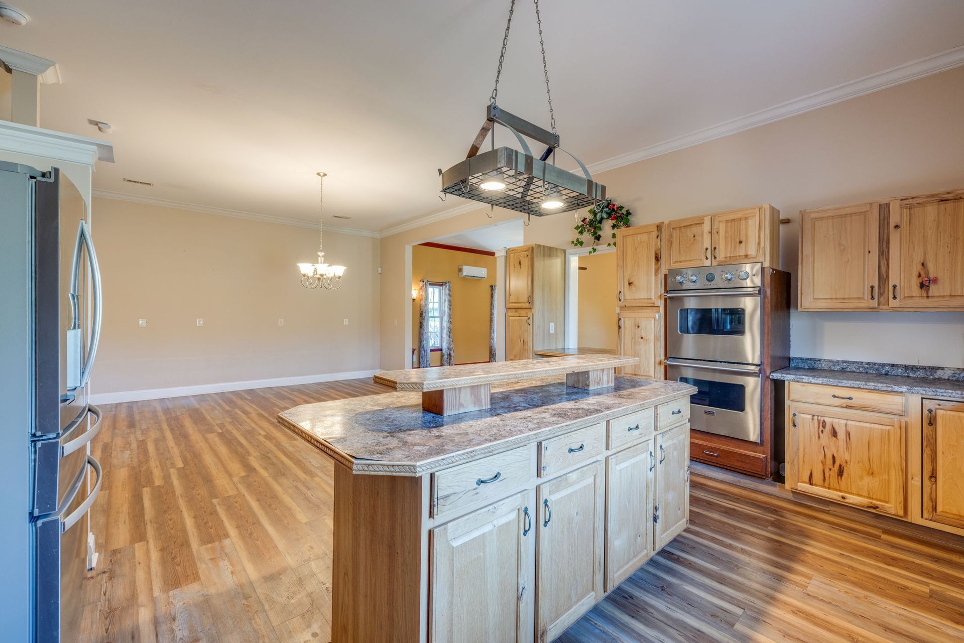 Spacious kitchen with wood cabinets, large island, stainless steel appliances, and hardwood floors