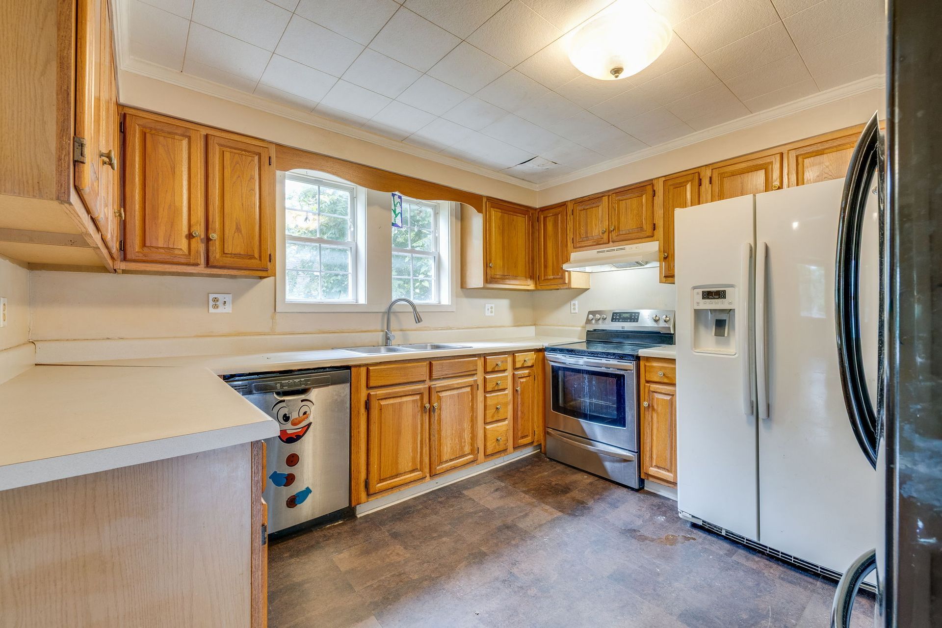 Bright kitchen with wood cabinets, white appliances, and a window over the sink