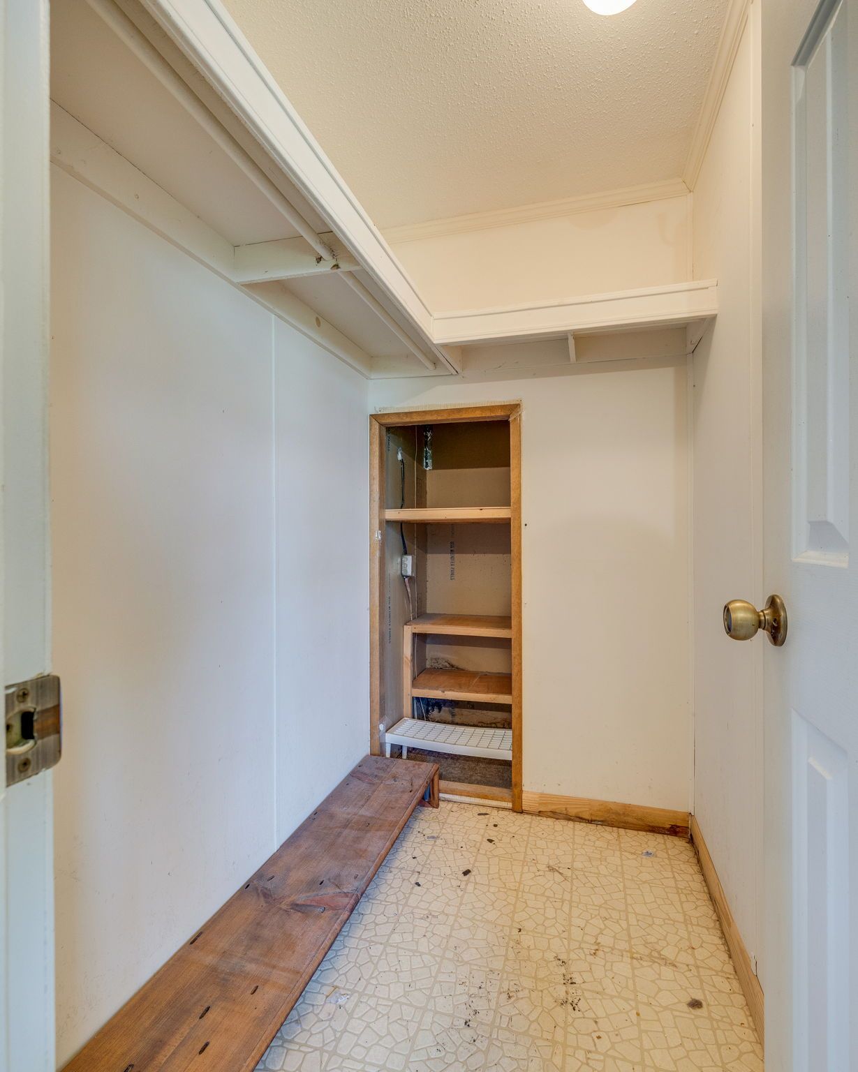 Empty closet with white walls, shelf above, and a built-in cubby unit at the back.