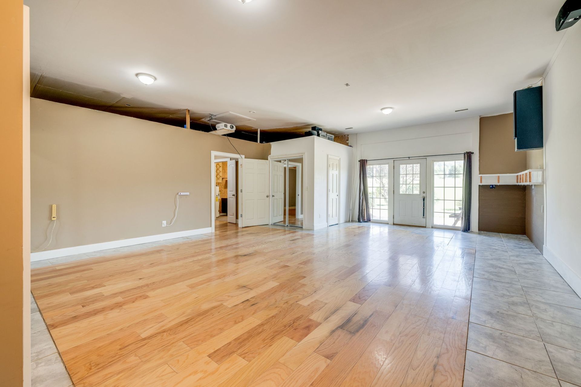 Empty open-plan living room with hardwood floors, beige walls, and sliding glass doors to a balcony