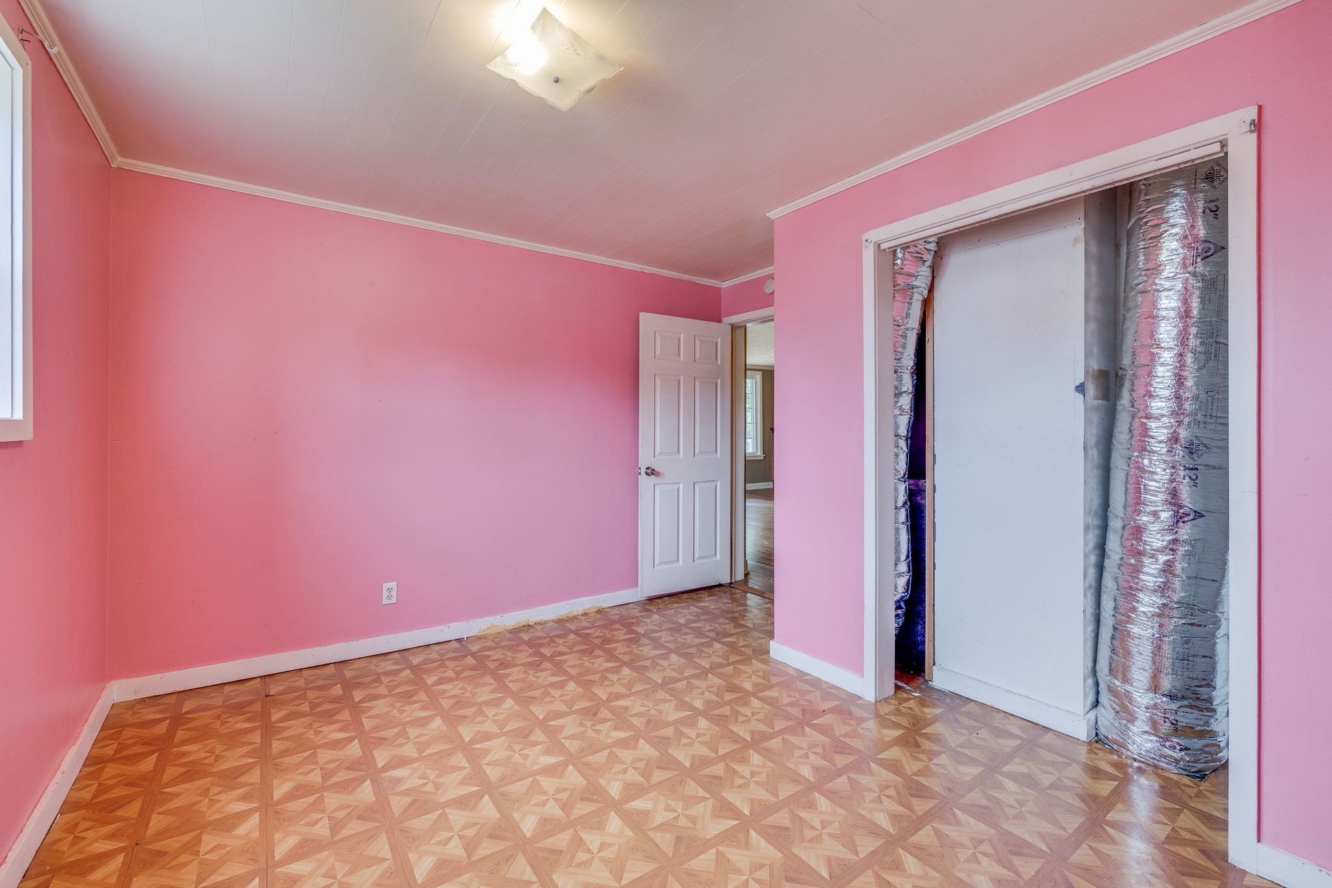 Empty pink bedroom with patterned floor and open closet door