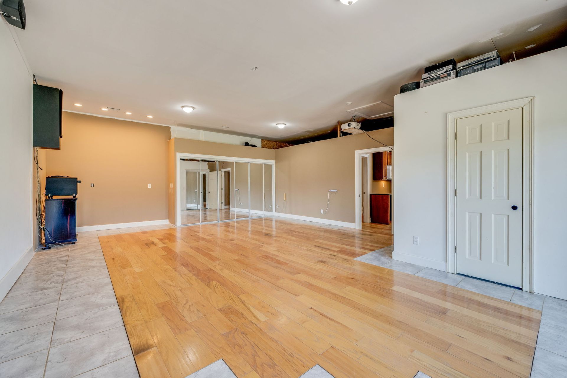 Spacious empty living room with hardwood floors, recessed lights, and sliding glass doors.