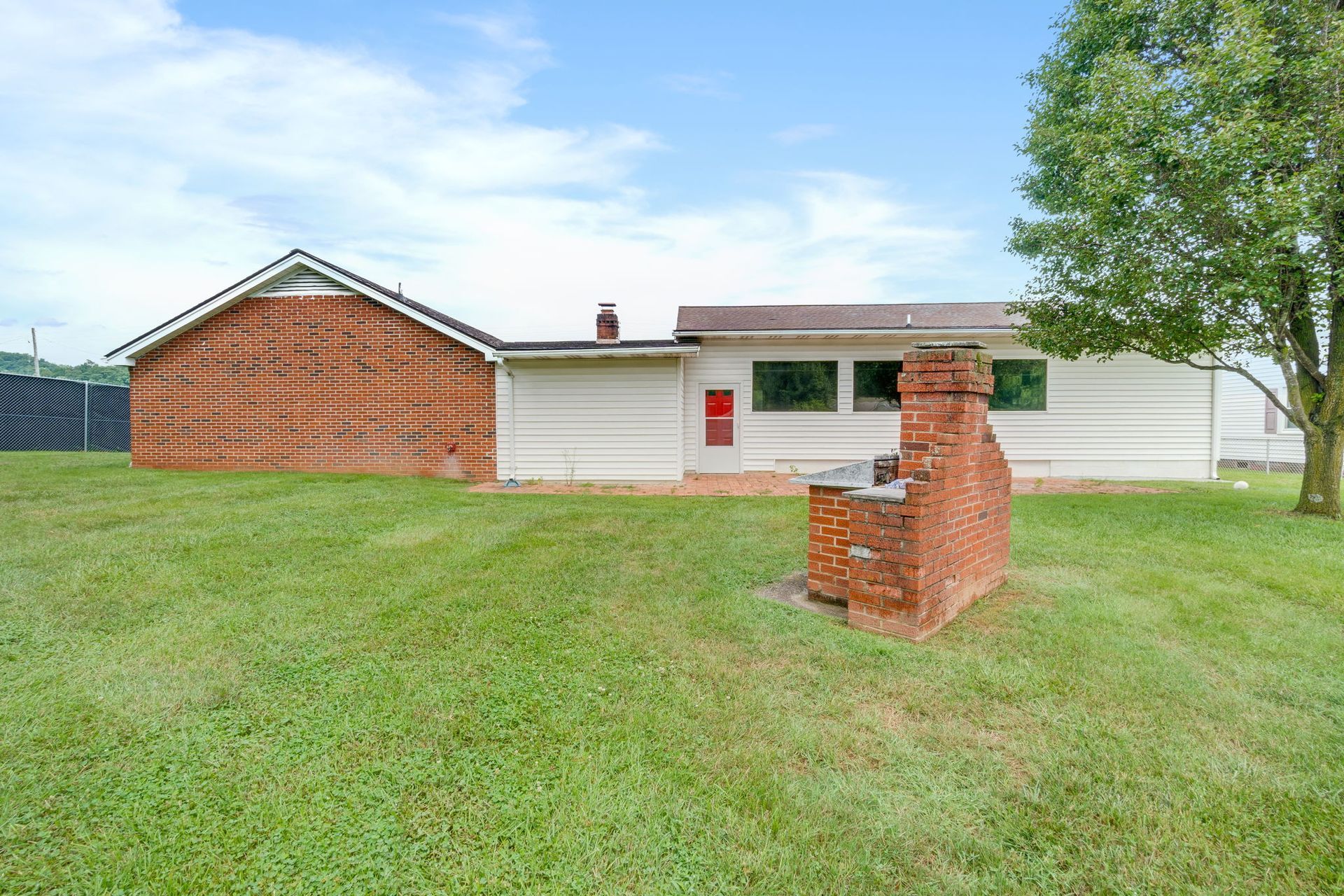 Small brick house with a grassy yard and a brick mailbox under a blue sky
